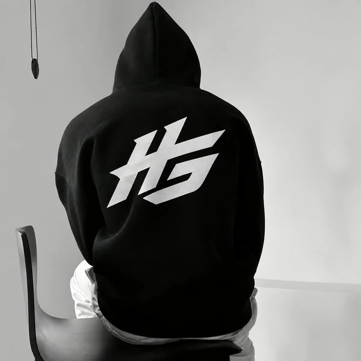 HSTLEGOODS HG monogram printed across the back of a black hoodie