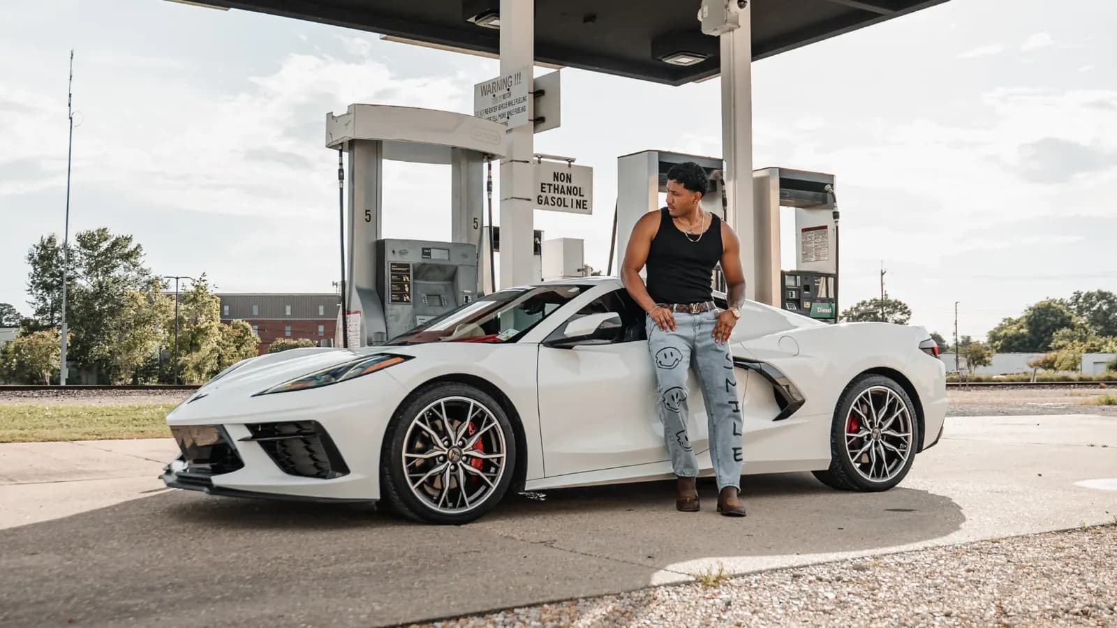 A white Corvette Stingray parked at a Lafayette gas station with its owner leaning on the door