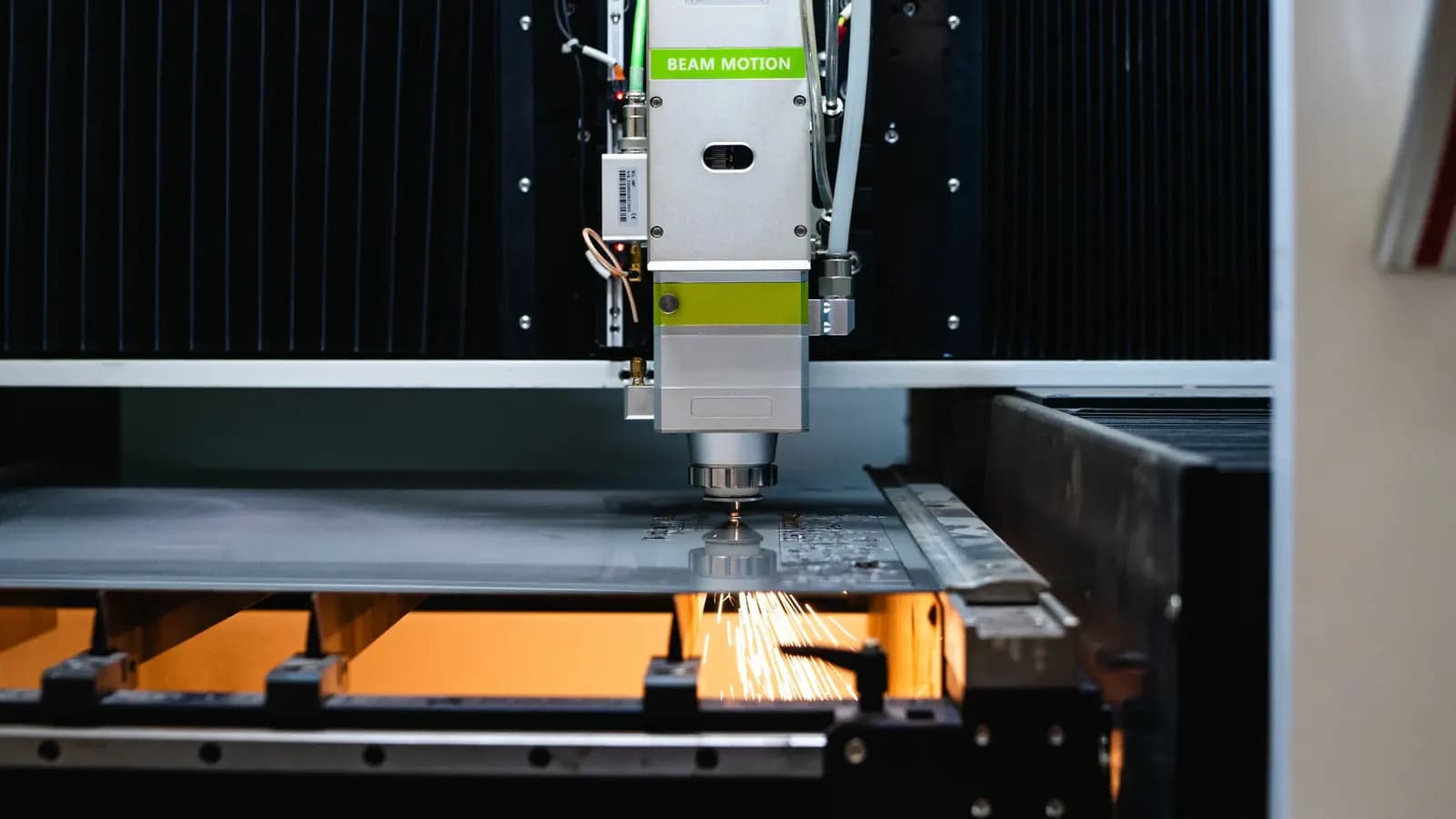 A fiber laser cutter throwing sparks as it cuts a sheet of steel