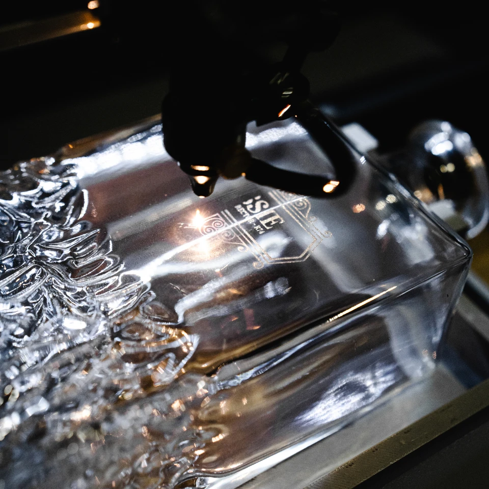 A laser engraving a logo into a glass decanter